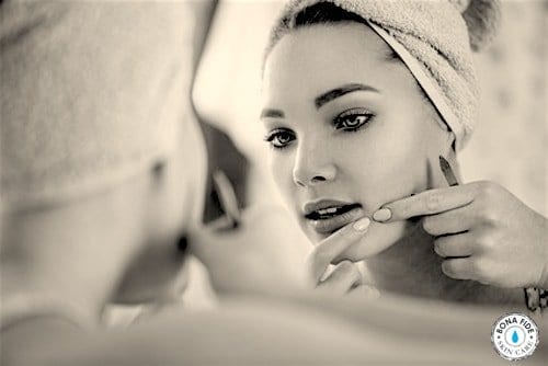 Woman squeezing skin in mirror