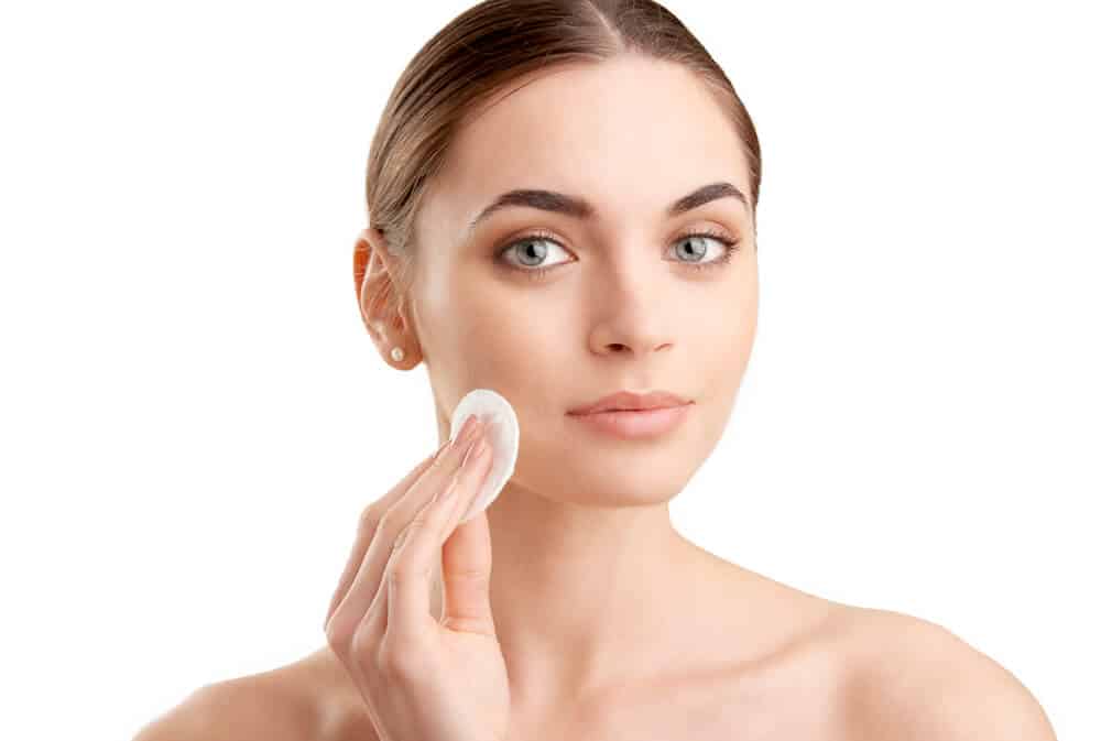 Woman holding a cotton pad to her face